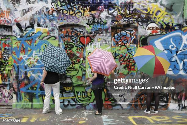 Three U2 fans add their names to the graffiti on the walls of Windmill Lane Studios in Dublin today.