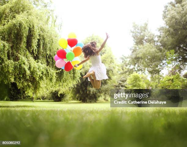 a 10 years old girl jumping with balloons in a park - girl 10 years old happy stock-fotos und bilder