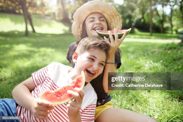 a brother and a sister eating watermelon together in a park - beach hat stock pictures, royalty-free photos & images