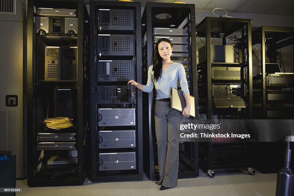 Woman holding laptop computer in server room