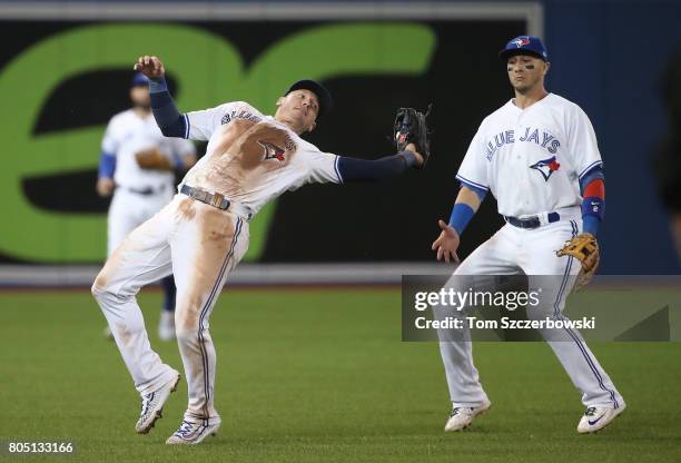 Josh Donaldson of the Toronto Blue Jays reaches over his shoulder to catch a pop up as Troy Tulowitzki watches in the ninth inning during MLB game...