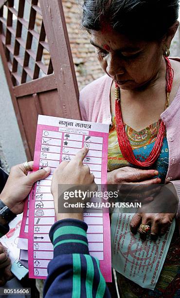 An activist of the Communist Party of Nepal points towards the symbol of his party on a ballot paper during a door to door election campaign rally by...