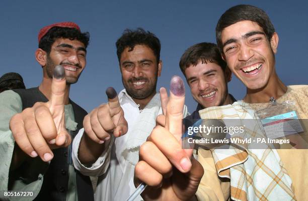 Voters show off their inked fingers after voting in Afghanistan's presidential election at a polling station in Lashkar Gah, despite the Taliban...