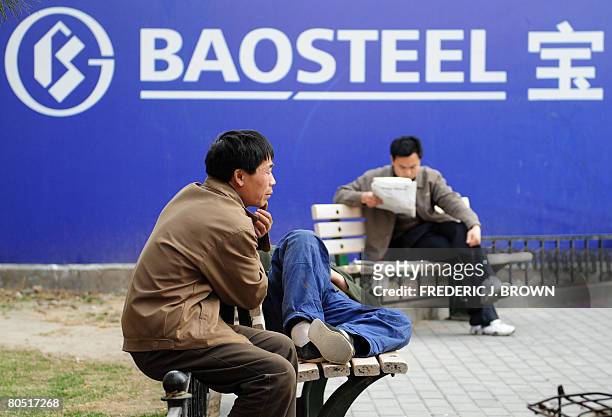 Man reads a newspaper beside an advertising billboard for Baosteel, China's largest steel maker, on April 4, 2008 in Beijing. China's top...