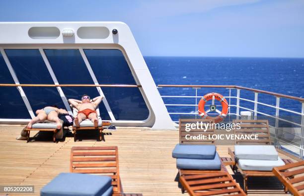 People sunbath on June 29, 2017 aboard the Cunard cruise liner RMS Queen Mary 2 sailing in the Atlantic ocean during The Bridge 2017, a transatlantic...