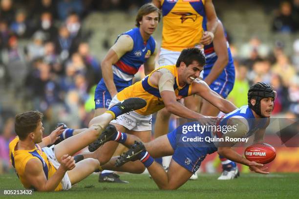 Caleb Daniel of the Bulldogs handballs whilst being tackled by Andrew Gaff of the Eagles during the round 15 AFL match between the Western Bulldogs...