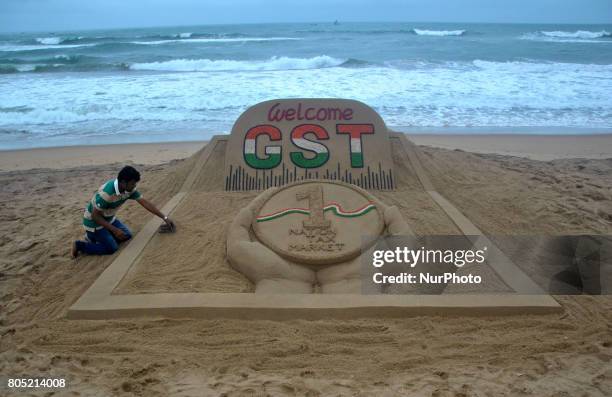 International sand artist create a sand sculpture at the Puri beach, 65 km away from the eastern Indian state Odisha's about the GST bill, that...