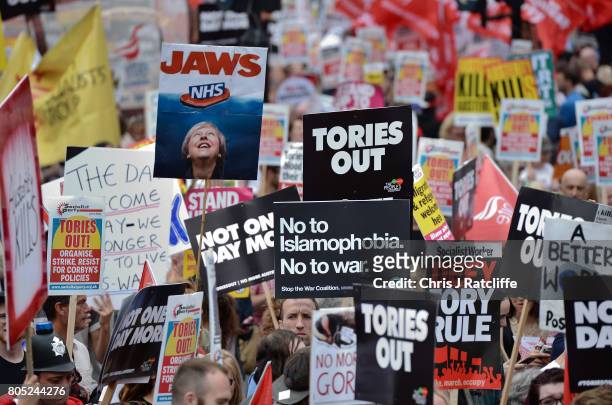 Demonstrators carry placards during the 'Not One Day More' march past Piccadilly Circus on July 1, 2017 in London, England. Thousands of protesters...