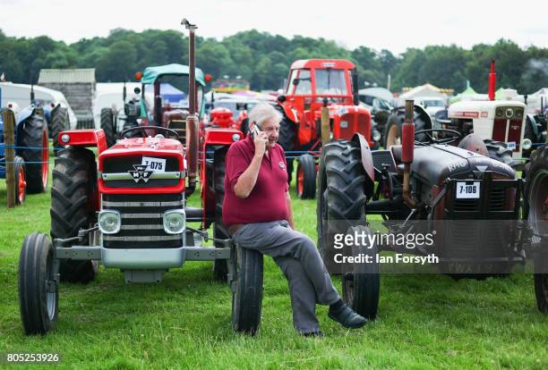 Man speaks on his phone as he sits on the wheel of a vintage tractor during the Duncombe Park Steam Rally on July 1, 2017 in Helmsley, United...
