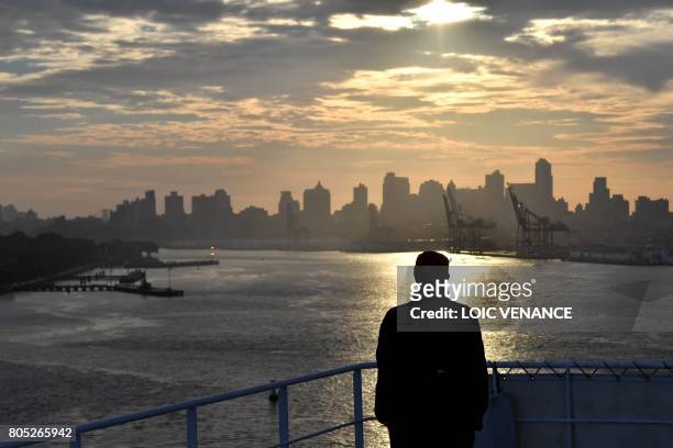 Passengers aboard the Cunard cruise liner RMS Queen Mary 2 look out as it arrives in New York after passing under the Verrazano bridge, finish line...