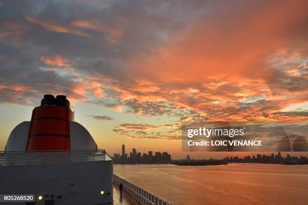 Passenger aboard the Cunard cruise liner RMS Queen Mary 2 looks out as it arrives in New York after passing under the Verrazano bridge, finish line...