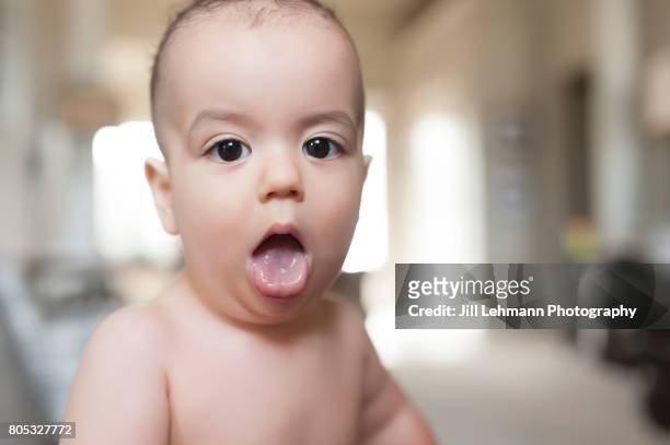 12 month old boy baby sticks his tongue out - tong uitsteken stockfoto's en -beelden