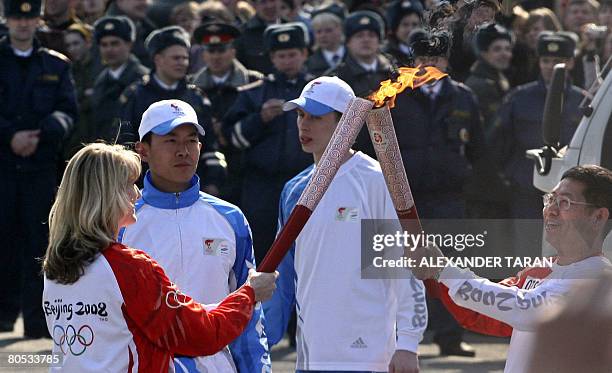 Russian speedskating Olympic champion Svetlana Zhurova receives the Olympic flame from Chinese Consul General in St.Petersburg, Tien Erhlung , during...