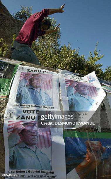 Zimbabwean man prays on the rock plastered with President Mugabe's posters in Harare on 5 April, 2008.Zimbabweans are still waiting for presidential...