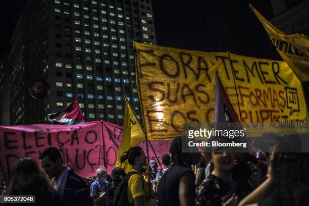 Demonstrators hold a large banner that reads "Out Temer And All Your Reforms And Corruption" during a general strike against labor and retirement...