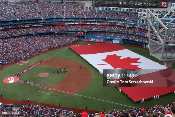 General view of Rogers Centre as a large Canadian flag is unfurled in the outfield on Canada Day during the playing of the Canadian national anthem...