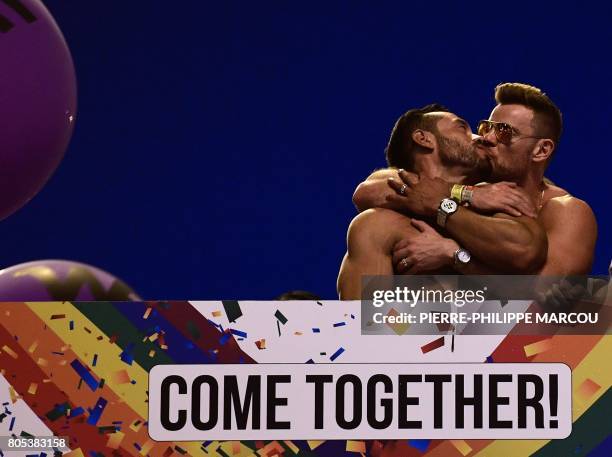 Two participants kiss eachother as they ride on a float during the WorldPride 2017 parade in Madrid on July 1, 2017. - Revellers took to the rainbow...