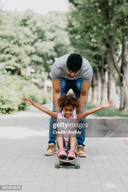 father pushing his daughter on the longboard - father longboard stock pictures, royalty-free photos & images