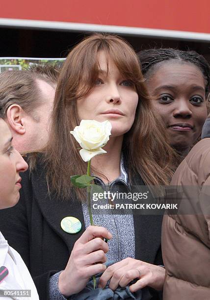 French first lady Carla Bruni-Sarkozy holds up a white rose next to France's human rights deputy minister Rama Yade , on April 6, 2008 in Paris, at...