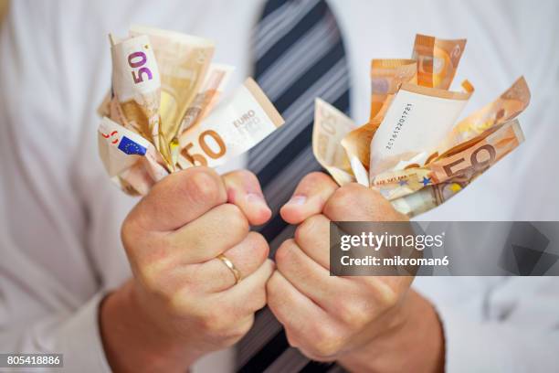 money addicted, greedy businessman squeezing money. love of money. - welvaart stockfoto's en -beelden