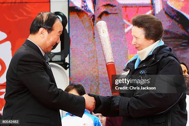 Princess Anne, the Princess Royal accepts the Olympic torch from Executive Vice-President of the Beijing Organizing Committee, Jiang Xiaoyu during...