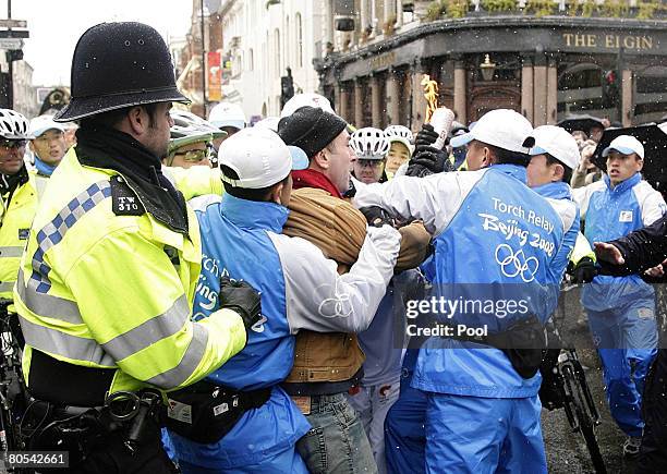 Police tackle a demonstrator during Konnie Huq's leg of the Beijing Olympics torch relay, heading towards Blenheim Cresent during the Beijing...