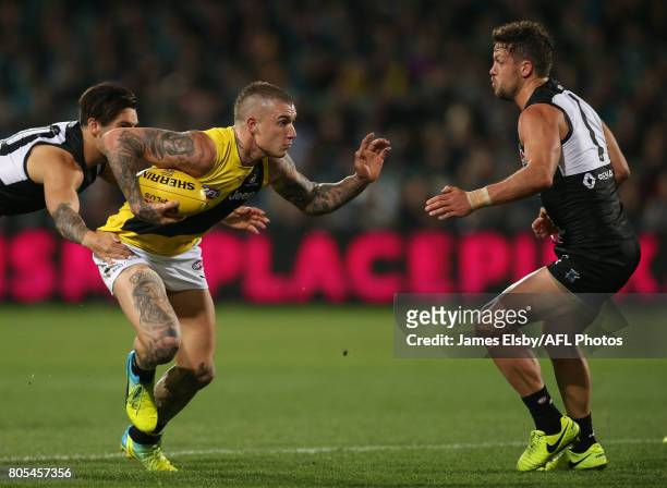 Chad Wingard and Travis Boak of the Power tackle Dustin Martin of the Tigers during the 2017 AFL round 15 match between the Port Adelaide Power and...