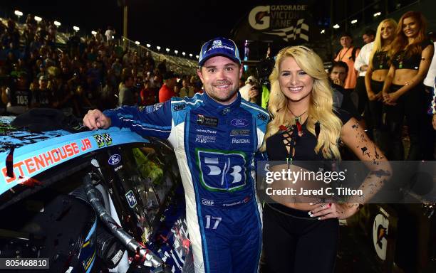 Ricky Stenhouse Jr., driver of the Fifth Third Bank Ford, and a Monster Energy girl pose with the winners decal in Victory Lane after winning the...