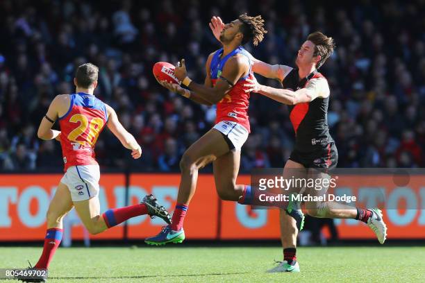 Archie Smith of the Lions competes for the ball against Michael Hartley of the Bombers during the round 15 AFL match between the Essendon Bombers and...