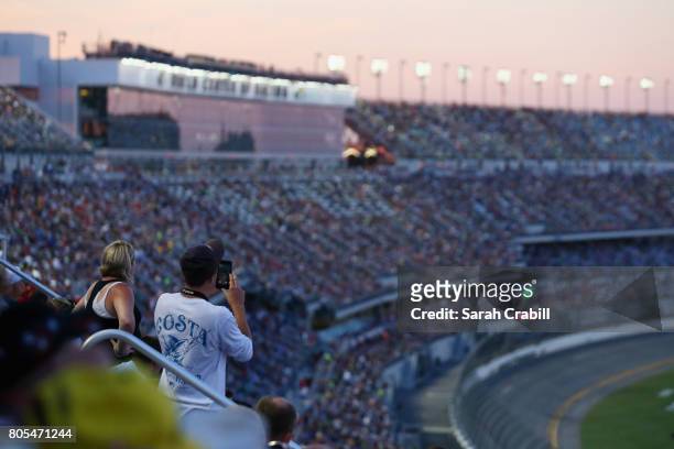 Fans look on as cars race during the Monster Energy NASCAR Cup Series 59th Annual Coke Zero 400 Powered By Coca-Cola at Daytona International...