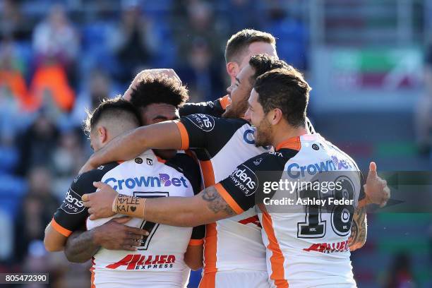 Kevin Naiqama of the Tigers celebrates his try with team mates during the round 17 NRL match between the Newcastle Knights and the Wests Tigers at...