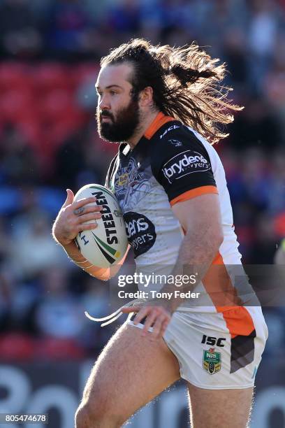 Aaron Woods of the Tigers runs the ball during the round 17 NRL match between the Newcastle Knights and the Wests TIgers at McDonald Jones Stadium on...