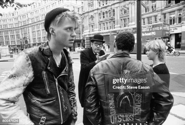 Bowler-hatted businessman argues with an anarchist on the back of whose jacket is written, 'Diminished Responsibility, UK SUBS', during the 'Stop the...