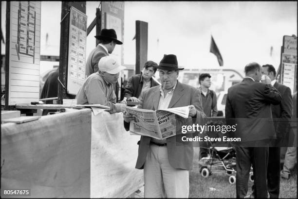 Tipster reading a newspaper at a bookmaker's stall at Epsom racecourse on Derby Day, 7th June 1997.