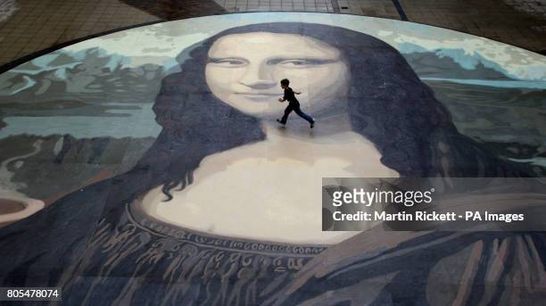 Luke Wharton-Jones runs across an attempt at the worlds biggest copy of the Mona Lisa during a photocall for it's unveiling at the Eagles Meadow...