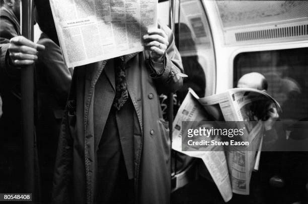 Commuters on a London Underground tube train reading their newspapers, March 1993.