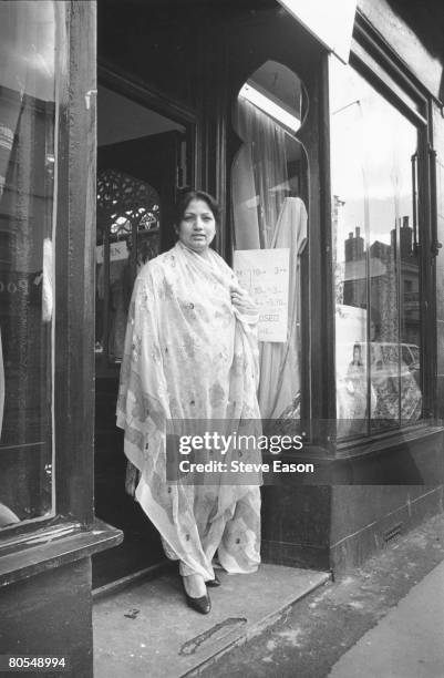 Woman in a sari standing outside a sari shop in Gloucester, 1986.