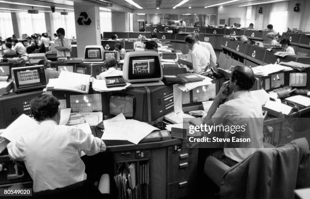 People at work on computers in an office at a National Westminster bank, circa 1990.
