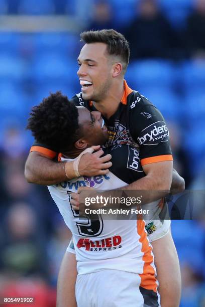 Luke Brooks of the Tigers celebrates his try with Kevin Naiqama during the round 17 NRL match between the Newcastle Knights and the Wests TIgers at...