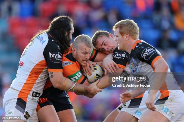 Mitch Barnett of the Knights is tackled by the Tigers defence during the round 17 NRL match between the Newcastle Knights and the Wests TIgers at...