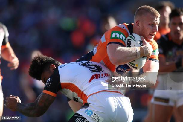 Mitch Barnett of the Knights is tackled by Kevin Naiqama of the Tigers during the round 17 NRL match between the Newcastle Knights and the Wests...