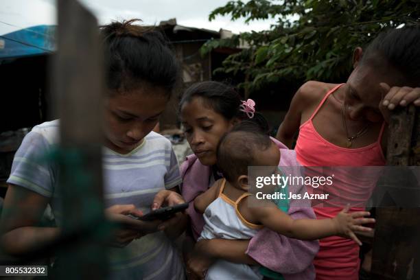 Maria Donna Bernardo reading a text message of a friend's phone on May 23, 2017 in an impoverished community in Tondo, Manila. Maria's husband Dennis...