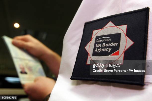 Border Agency officer checks a passport in the North Terminal of Gatwick Airport, Sussex.