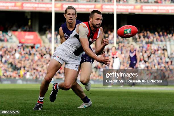 Jarryn Geary of the Saints handpasses the ball under pressure from Nat Fyfe of the Dockers during the round 15 AFL match between the Fremantle...