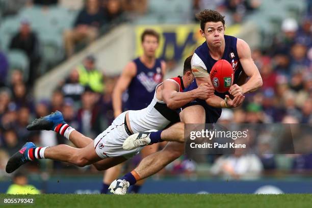 Lachie Neale of the Dockers looks to handball while being tackled by Koby Stevens of the Saints during the round 15 AFL match between the Fremantle...