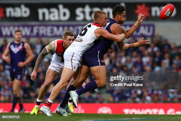 Michael Johnson of the Dockers gets his handball away while being tackled by Sebastian Ross of the Saints during the round 15 AFL match between the...