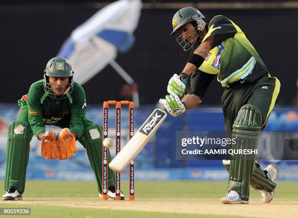 Pakistani cricket team captain Shoaib Malik hits a stroke as Bangladeshi wicketkeeper Dhiman Ghosh looks on during the first One-Day International...