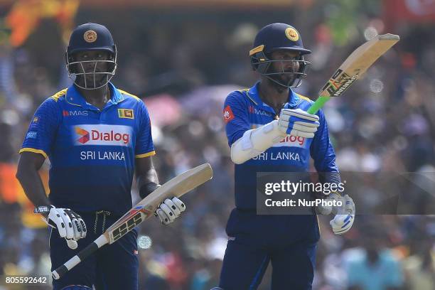 Sri Lankan cricket captain Angelo Mathews looks on as Upul Tharanga raises his bat after scoring 50 runs during the 2nd One Day International cricket...