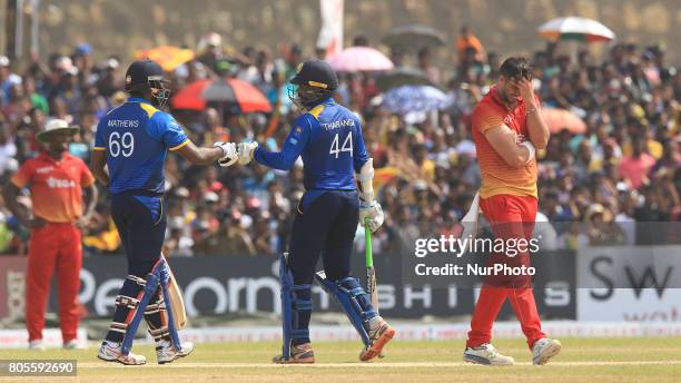 Sri Lankan cricket captain Angelo Mathews and Upul Tharanga tap their gloves as Zimbabwe captain Graeme Cremer reacts during the 2nd One Day...