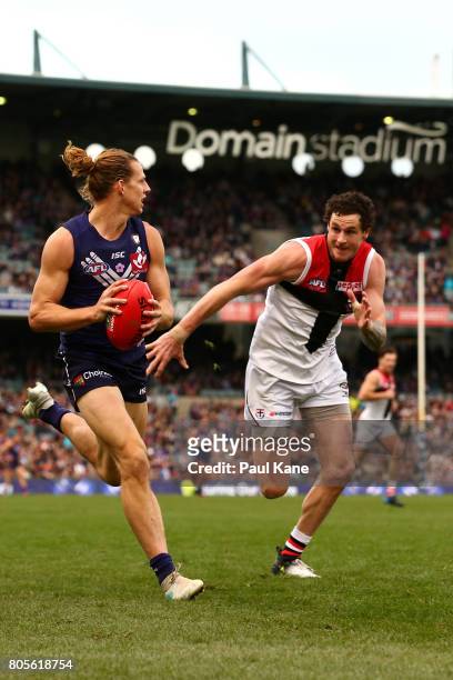 Nathan Fyfe of the Dockers looks to pass the ball against Jake Carlisle of the Siants during the round 15 AFL match between the Fremantle Dockers and...